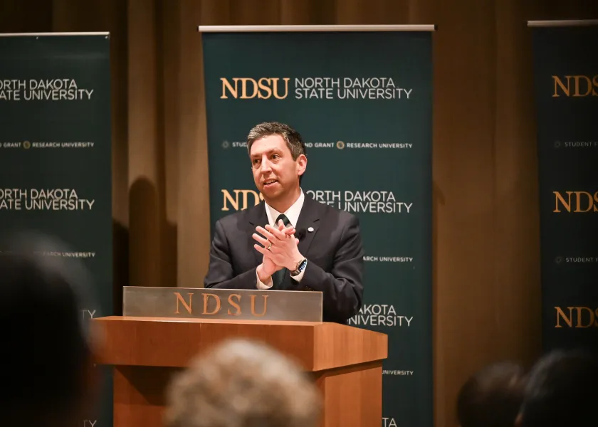 North Dakota State University presidential candidate Bernie Savarese, stands behind a podium while talking to an audience on NDSU's campus.
