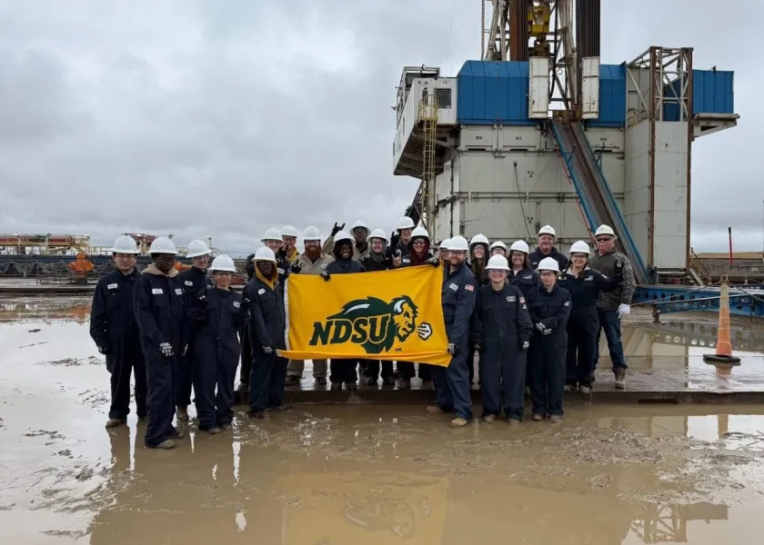 Students in NDSU's Bison to the Bakken program pose for a photo while holding a NDSU flag.