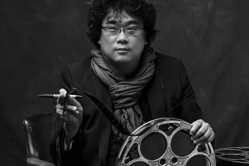 Joon-Ho staring straight at camera holding film reel.