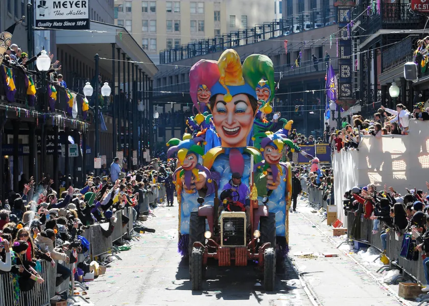 mardi gras parade with colorful jester float with crowds viewing the parade