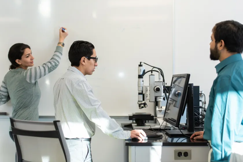 graduate engineering students work together at the whiteboard and computer