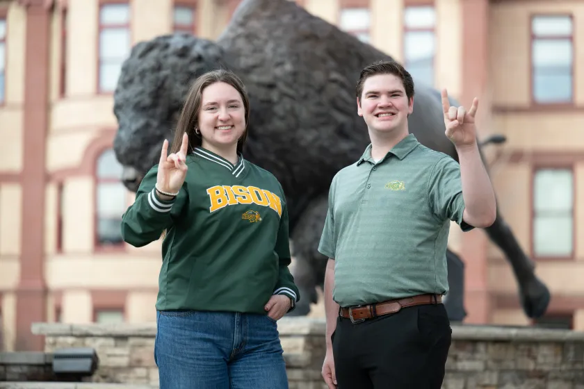 Student body president, Kaley Quam, and student body vice president, Drew LeBrun, pose for a photo in front of NDSU's Bison statue.