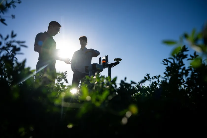 An NDSU professor and student stand by a drone in a field.