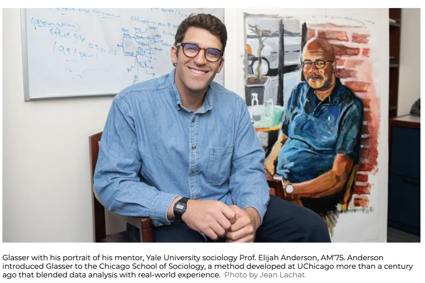 man with glasses smiling at camera with painting of man in background