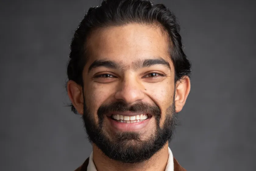 Aditya Goyal in a brown suit jacket smiling in a headshot.