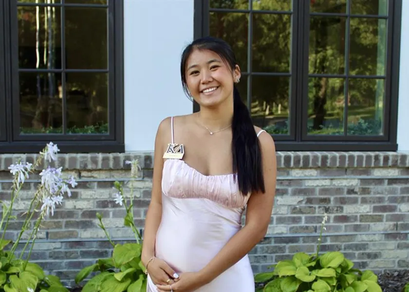 NDSU student Sarah Kruse standing outside smiling in a pale pink dress.