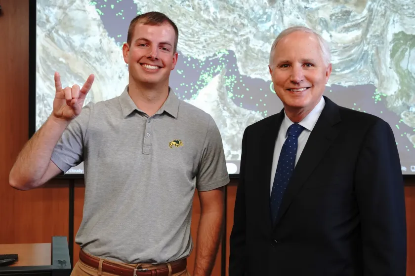 NDSU Student Will Ellison with horns up standing next to Jay Debertin president and CEO of CHS