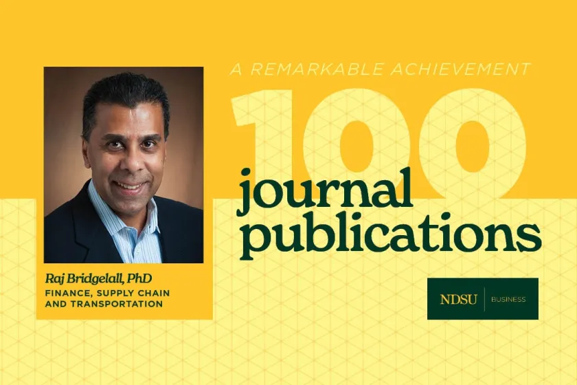 Raj Bridgelall, associate professor in the NDSU College of Business, poses for a photo with the words "A remarkable achievement 100 journal publications."