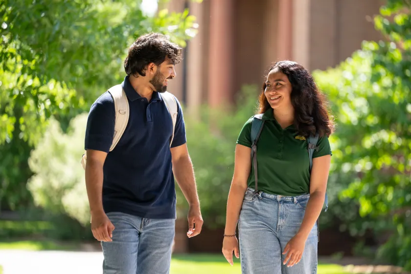 Two NDSU students smile at each other as they walk away from Putnam Hall.