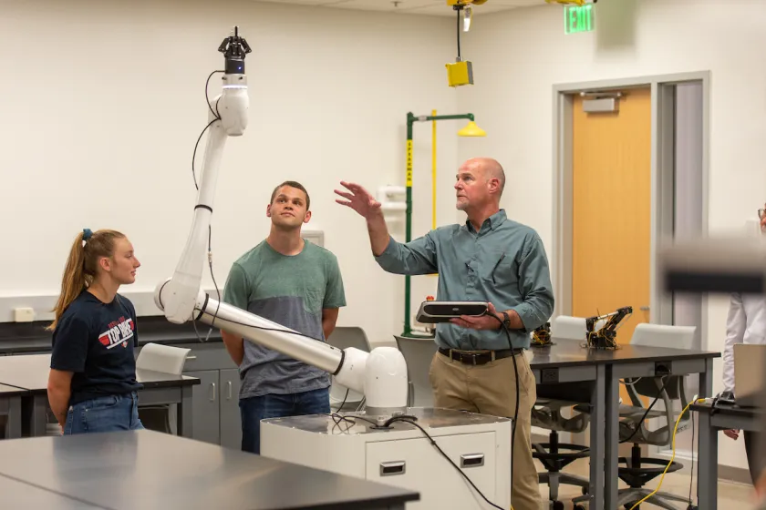 students work with a robotics arm alongside their instructor