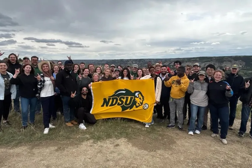 NDSU students hold a NDSU flag while posing for a photo.