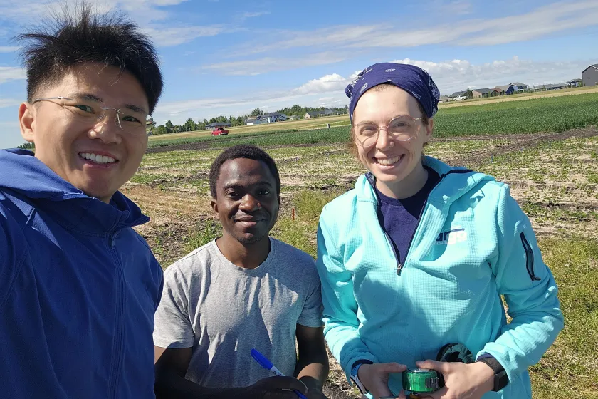 NDSU assistant professor Kiang Lang two students in a field under a blue sky with scattered clouds. 
