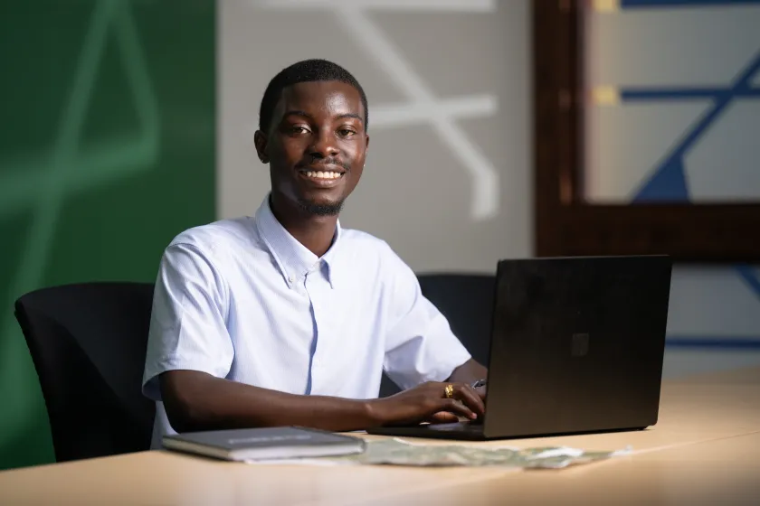 An NDSU student in professional attire smiles while working on a laptop