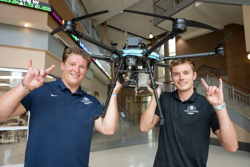 Two students hold a drone