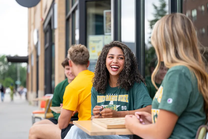NDSU students sit and talk around a table outside 