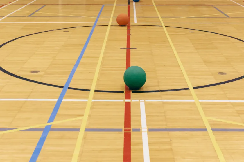 Red, orange and blue dodgeballs lined up on center court in a gym