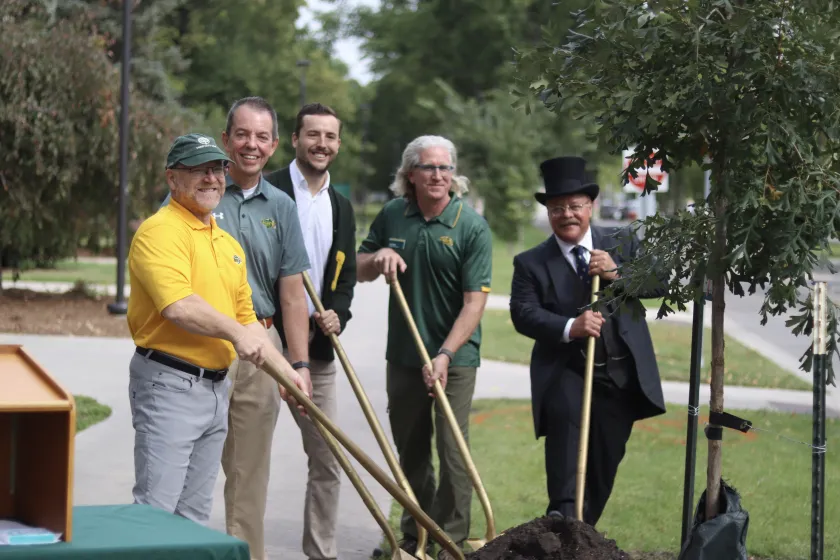 (l-to-r): Thomas Claeys, President Marshall Stewart, Robbie Lauf, Todd West, and President Teddy Roosevelt plant a tree for Trees Bowl.
