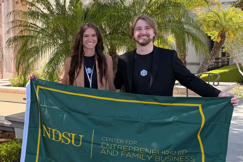 Two NDSU students hold a flag that says NDSU Center for Entrepreneurship and Family Business