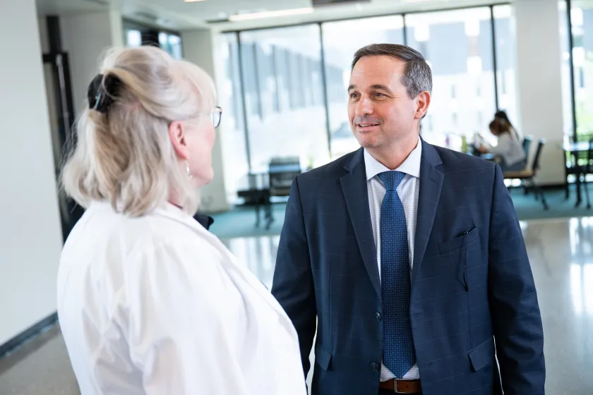 A man in a suit talks to a woman in a doctor's coat