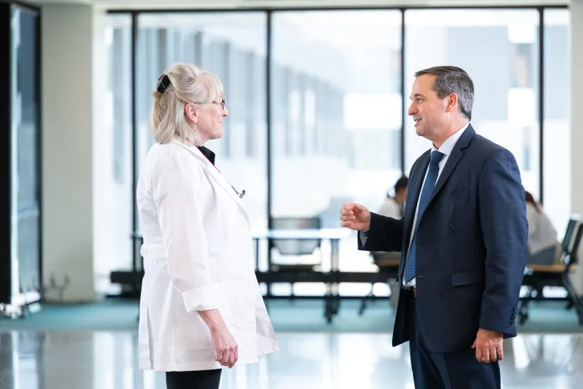A man in a suit talks to a woman in a doctor's coat