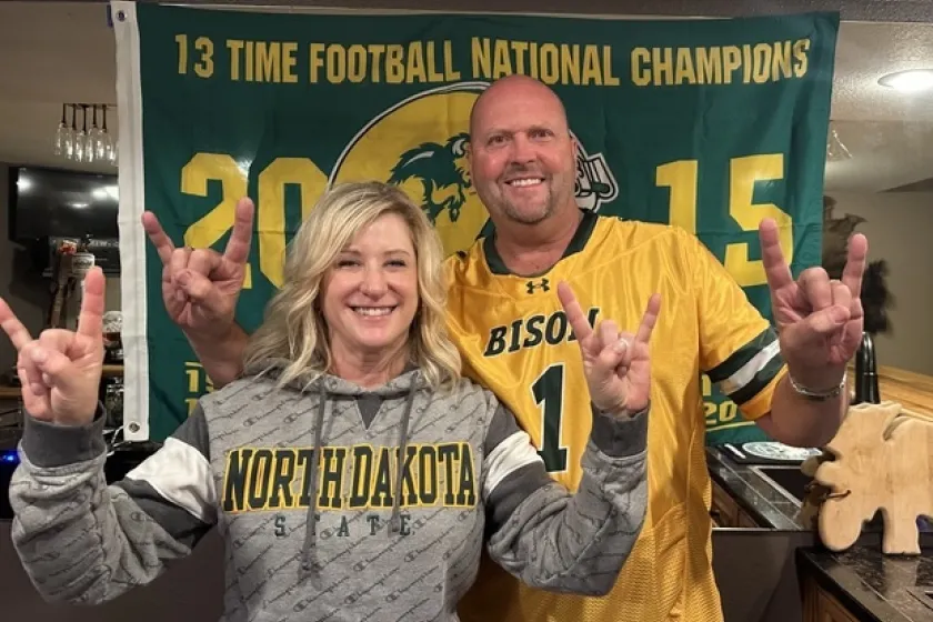 A man and a woman wear NDSU gear and smile