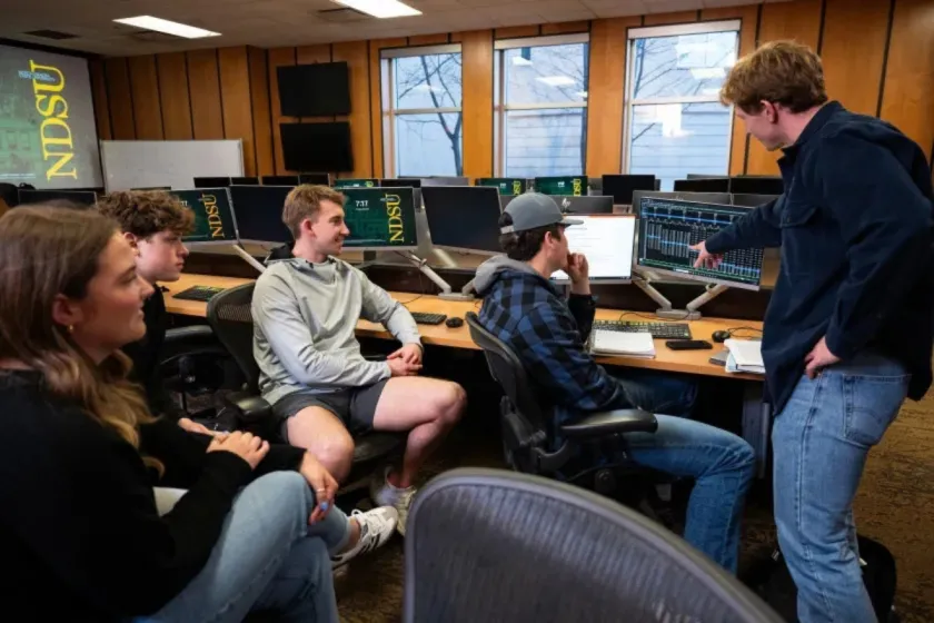 Students discuss work displayed on a computer in an NDSU classroom.