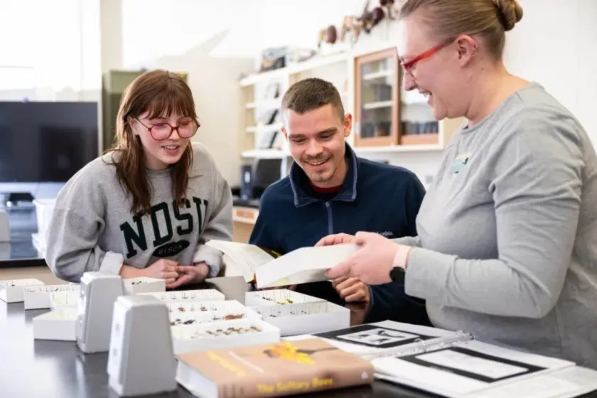 NDSU students and an instructor examine materials together in a lab.