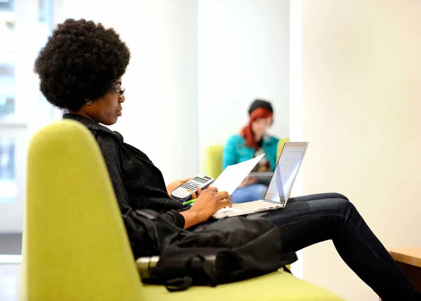Student studying using laptop and calculator