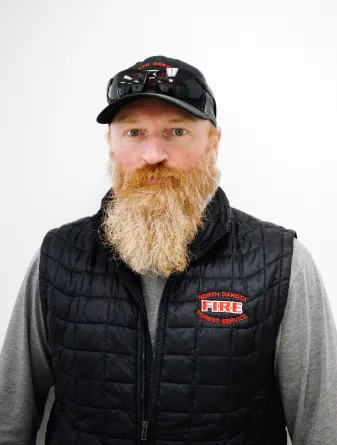 A man with a long red beard and sunglasses on top of his head with a baseball cap