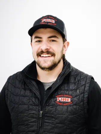 A man with a brown mustache and beard smiling and wearing a baseball cap