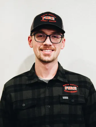 A man with glasses and a baseball cap smiling
