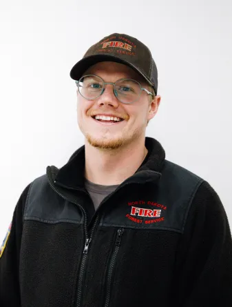 A man with glasses and a baseball cap smiling