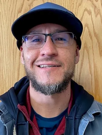 A man with glasses and a ball cap smiles