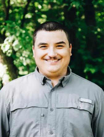 A Man smiling with trees in the background