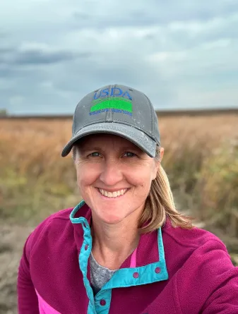 Klug wearing a baseball cap while smiling confidently at camera.