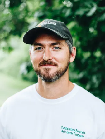 A man with a baseball cap grins