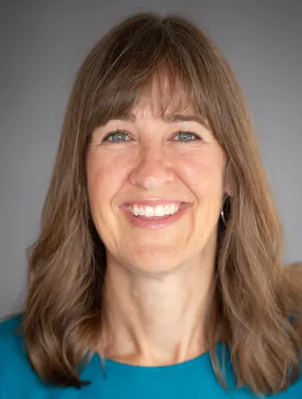 Britt Heidinger wearing a teal colored shirt in front of a gray background.