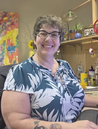 Shannon Ueker, Graduate Programs Assistant, smiles at her desk