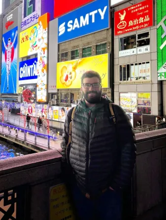 man standing in front of multiple electronic billboards