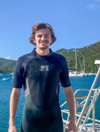 Student in snorkeling gear in front of beach