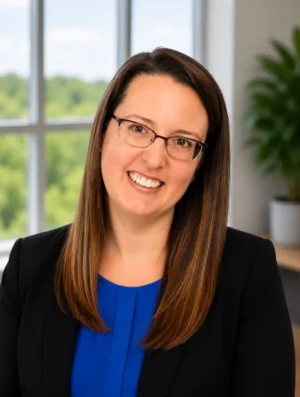 Jessica is a caucasian middle aged woman with dark brown long hair and brown eyes with glasses. She is wearing a blue shirt and black blazer. 