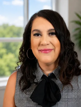 Marisa is a middle aged woman with dark brown shoulder length hair and brown eye. She is wearing a black and white plaid shirt. 