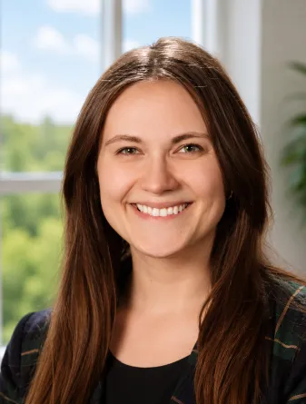Hannah is a caucasian young woman with long brown hair and green eyes. She is wearing a black shirt.