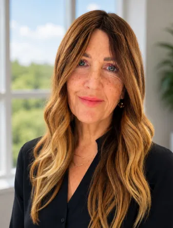 Clare is a caucasian woman with light brown long hair and blue eyes. She is wearing a black shirt.