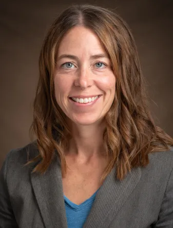 Woman in blue shirt and grey jacket