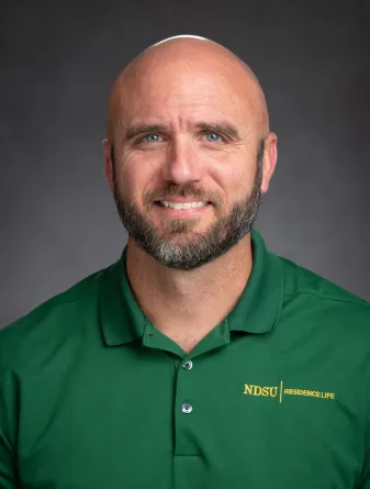 jason medders headshot, wearing green ndsu residence life polo