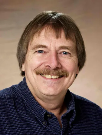 Dennis Tallman smiling confidently at the camera.