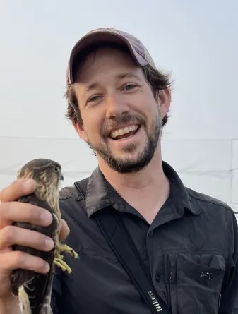 Samuel Lane smiling confidently and holding a bird.