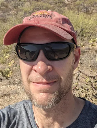 Prasifka wearing a baseball cap and sunglasses while looking confidently at camera.