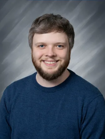 Alex Torson smiling confidently at camera.